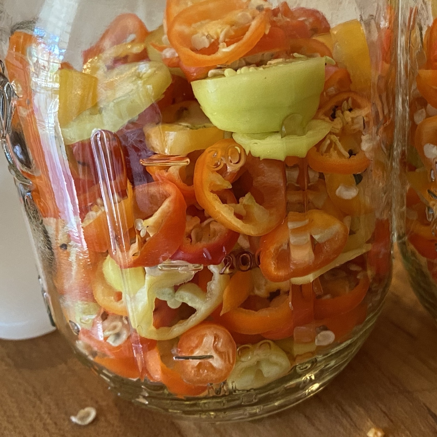yellow to red sliced santa fe peppers, in a jar, ready for pickling brine.