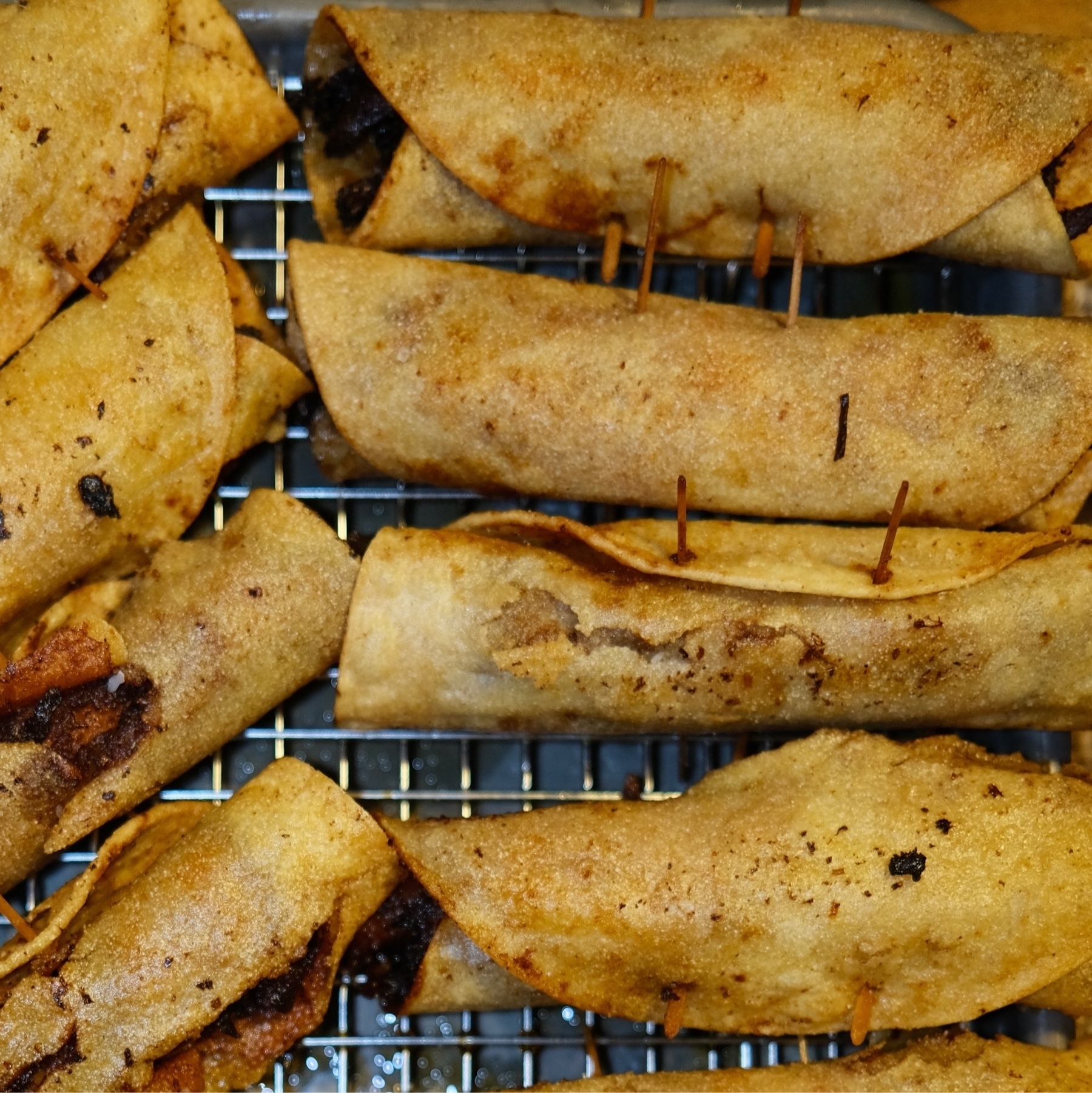 browned fried taquitos on a grid rack