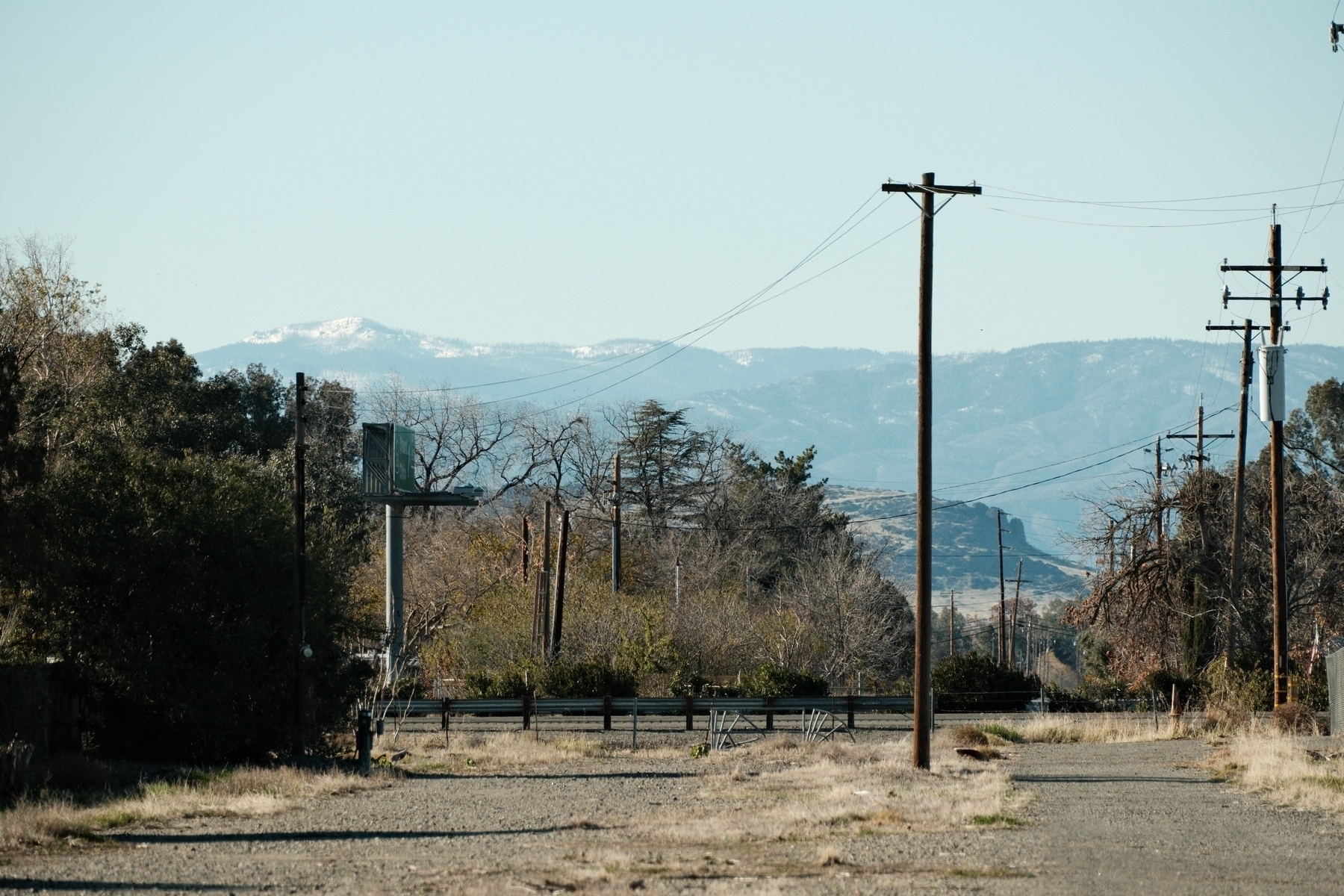 a distant snowy peak on the left and a vertical butte on the right. multiple power lines cross the view. 