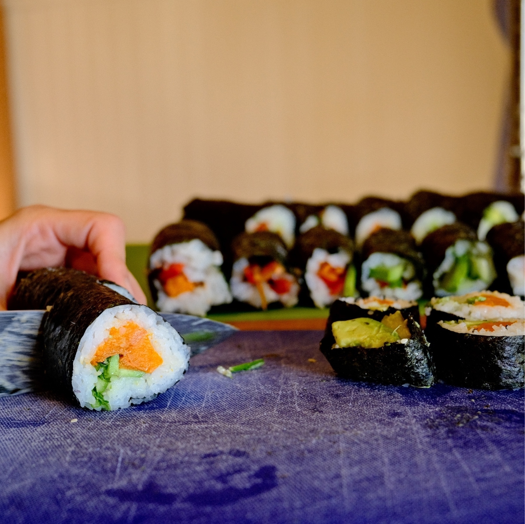 cutting rolls of sushi on a blue cuttingboard
