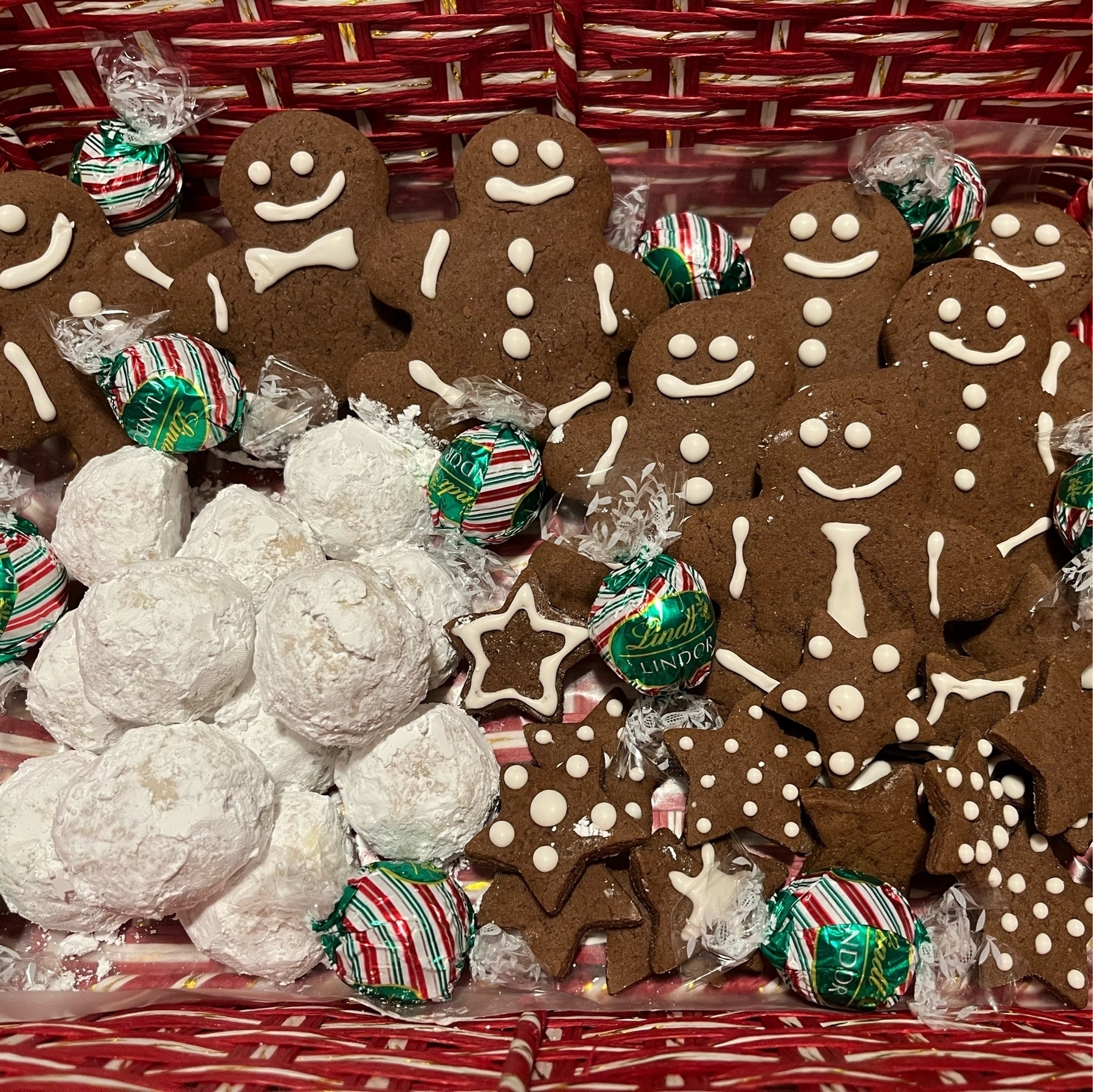 ginger bread people with snow balls, Lindtt chocolayes, all in a red and white basket.