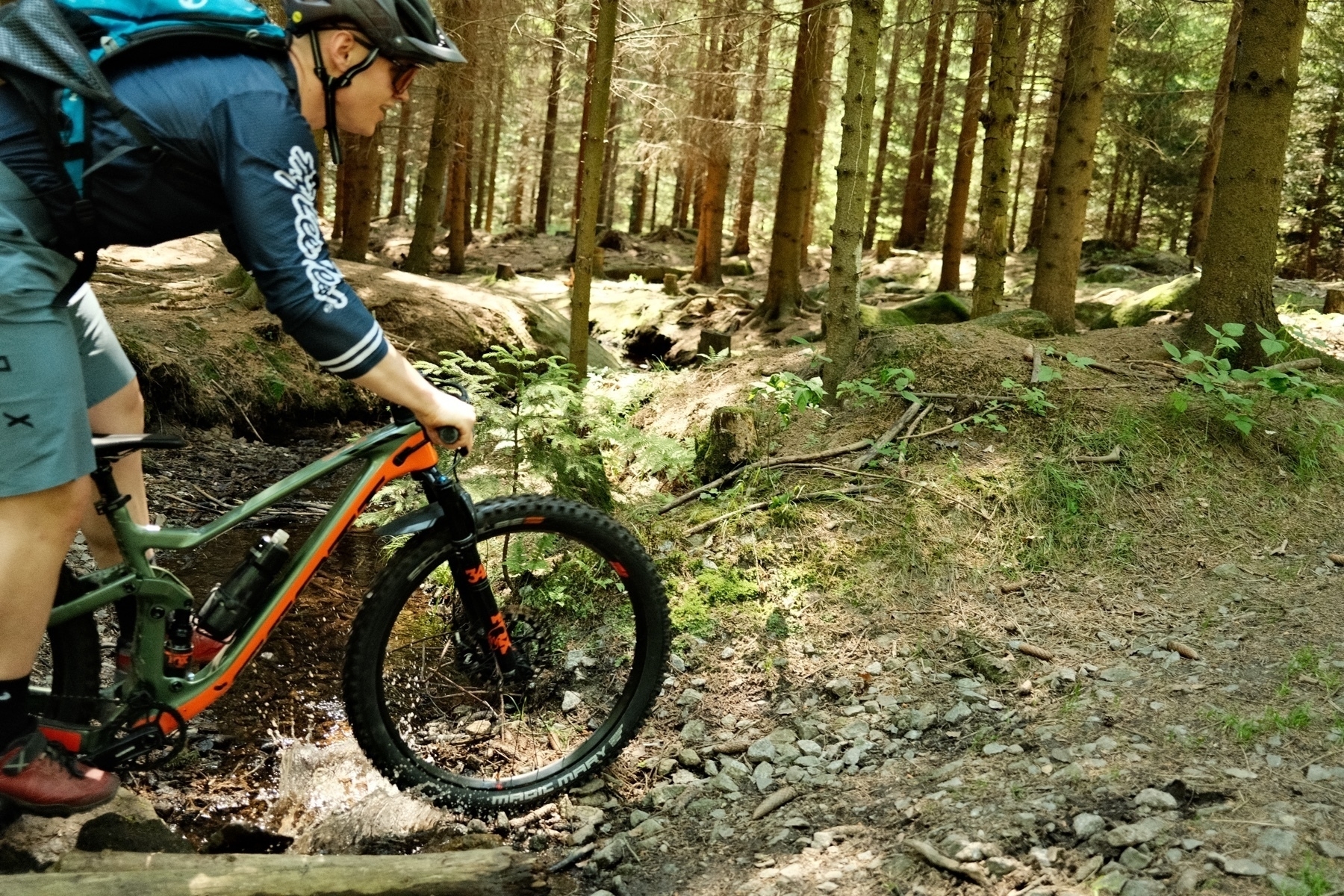 mountain biker crossing a stream under forest cover
