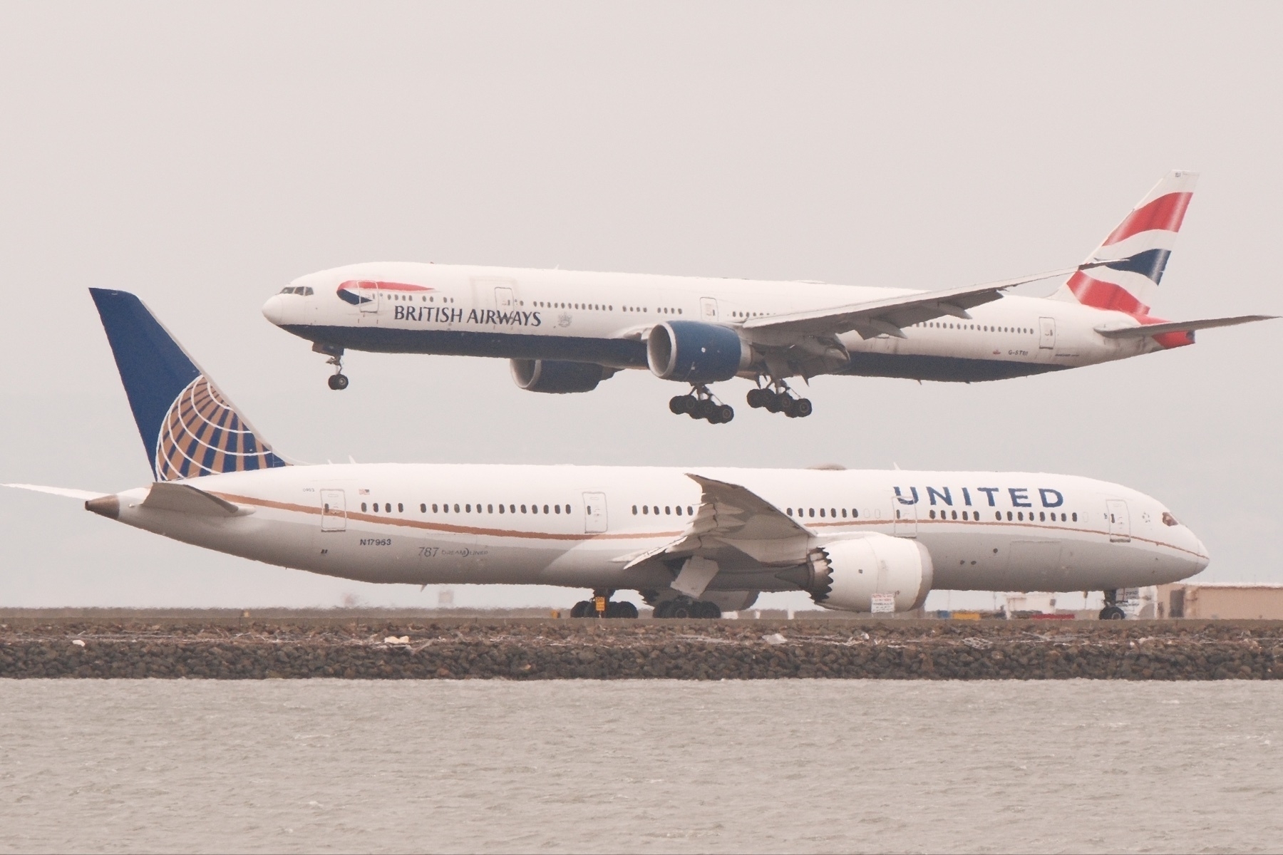 A United 787 is turning on to SFO 28L, while above it, a British Airways 777 lands on 28R.